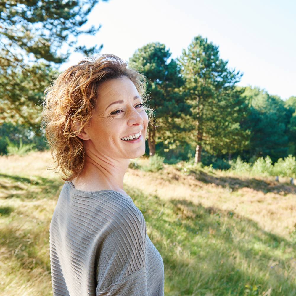 woman smiling near trees and grass