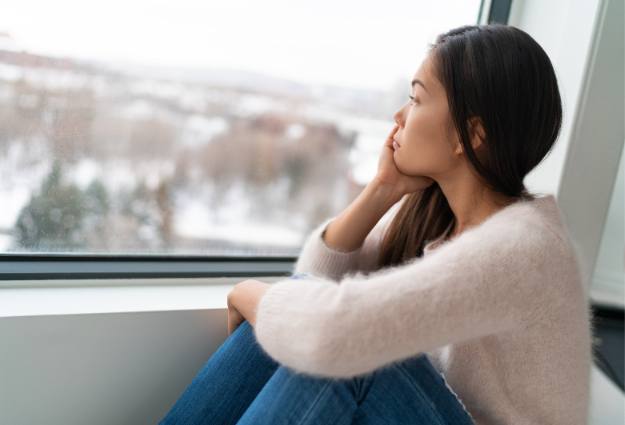 woman sadly looking out the window