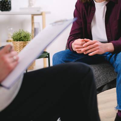 person speaking to therpist with clipboard