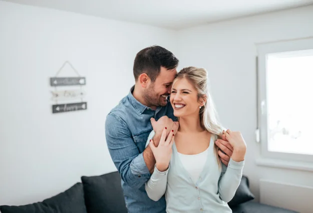Happy couple embracing and smiling together at home
